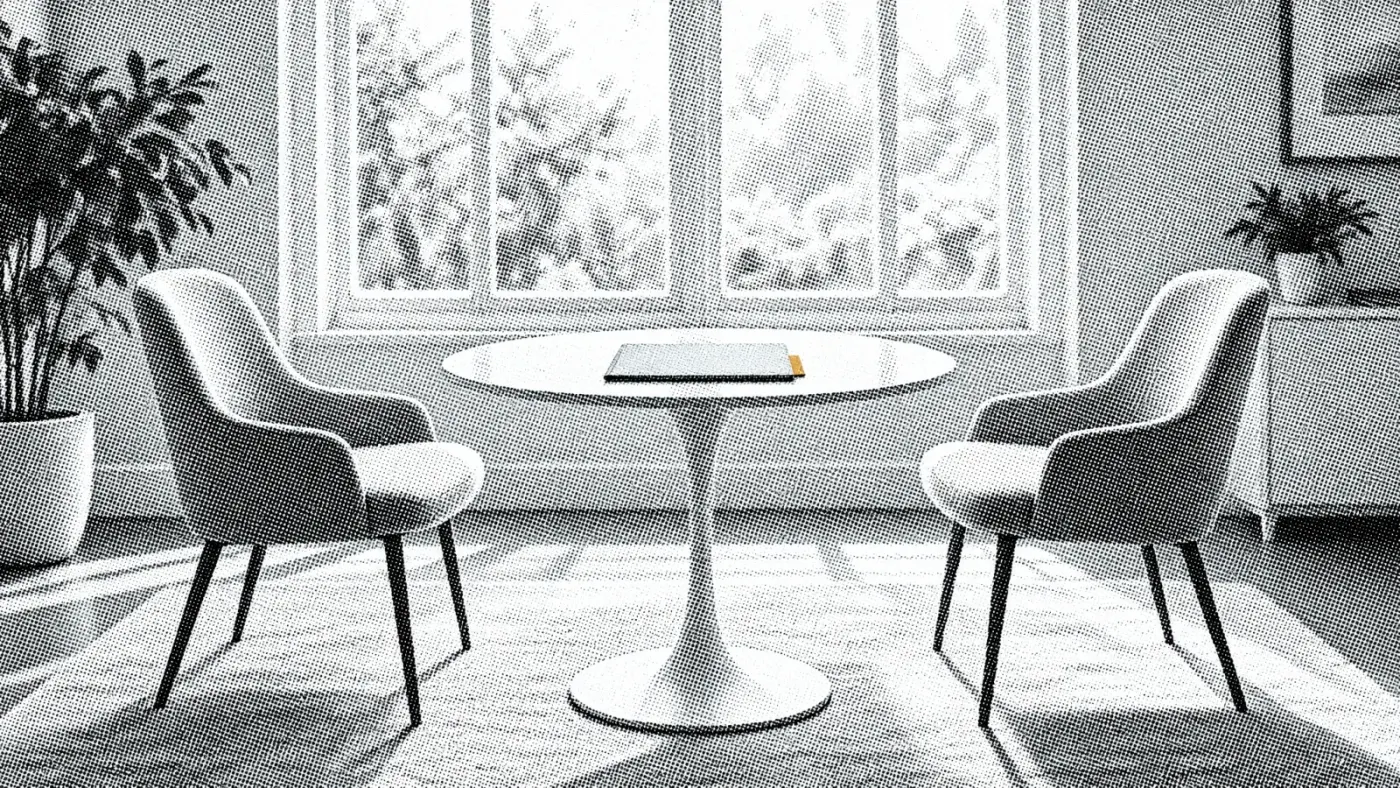 Two empty chairs facing each other across a small table with a single folder on it
